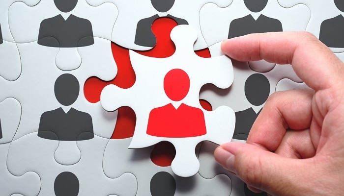 Selecting right people for organization's success. Think different and unique concept. 
Putting last jigsaw puzzle piece with red businessperson.