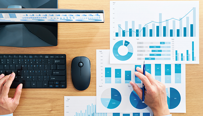 Top view of business man analyzing figures. Many reports and desktop computer.